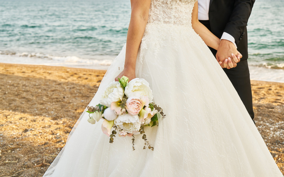 Paar heiratet am Strand im Anzug und Hochzeitskleid