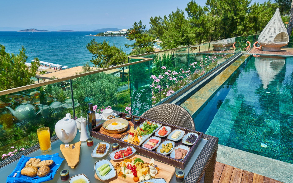 Pauschalurlaub: Gedeckter Tisch mit Frühstück am Pool eines Hotels mit Meerblick