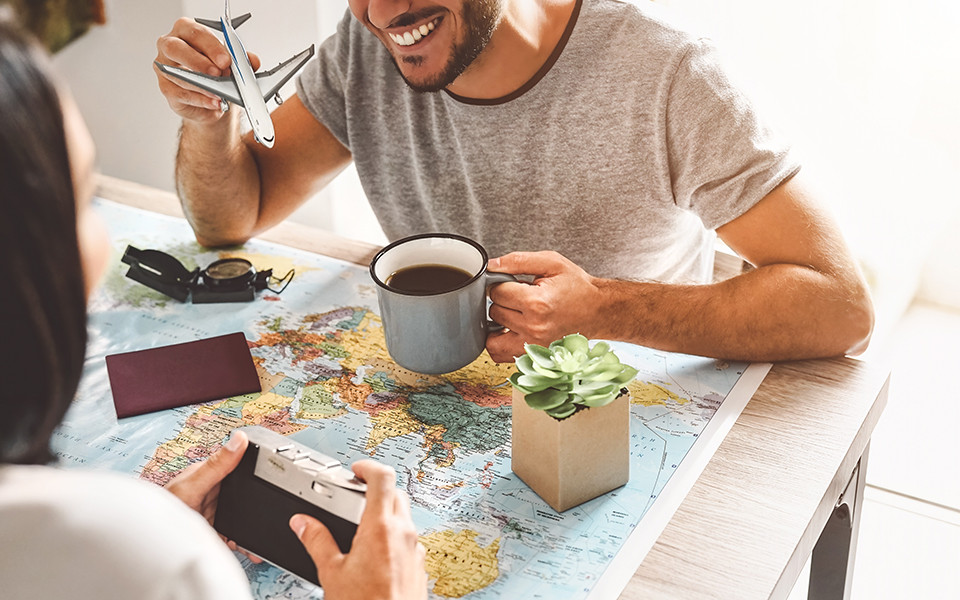 Mann sitzt am Tisch mit Kaffee, Reisepass und Landkarte