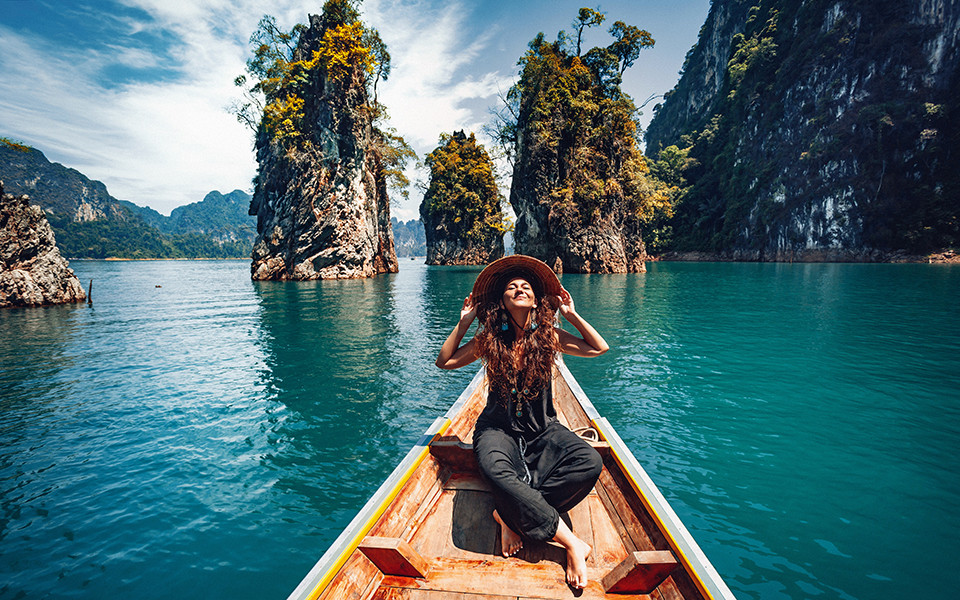 Frühbucher Rabatte: Frau mit Hut auf einem Boot in Thailand