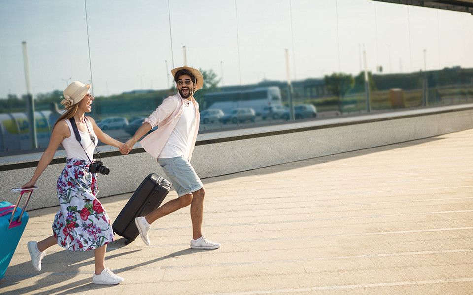 Paar startet in den Last-Minute-Urlaub mit gepackten Koffern