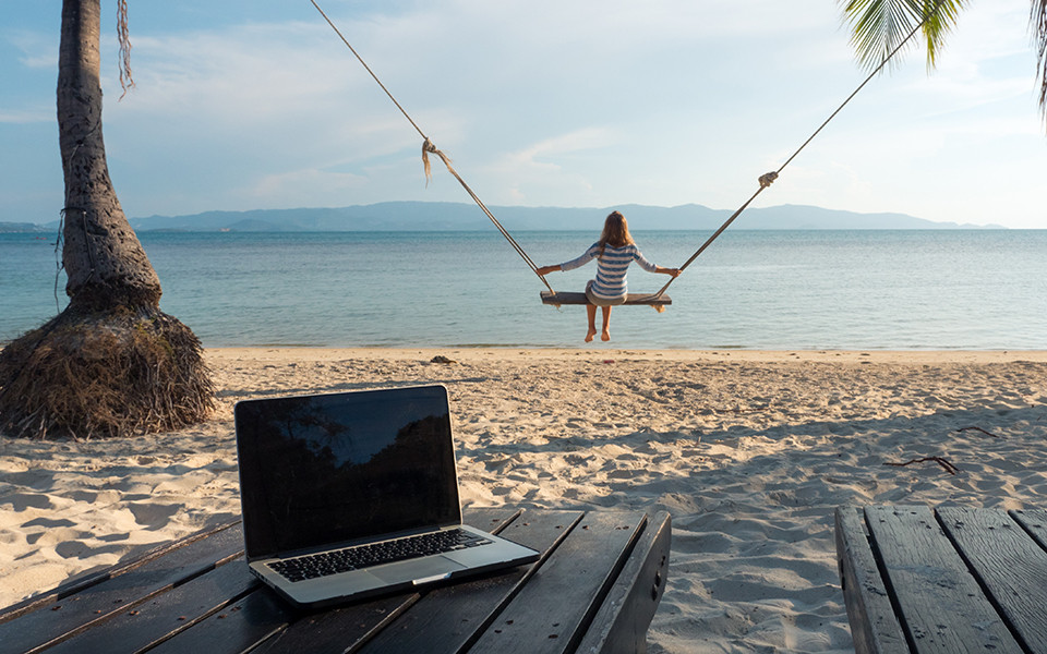 Frau auf Schaukel am Meer mit Laptop