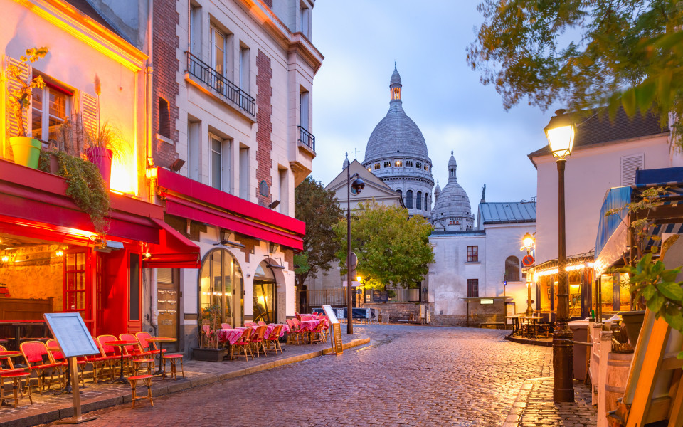 Abendstimmung im Pariser Künstlerviertel Montmartre mit Straßencafés und Blick auf die Basilika Sacré-Cœur