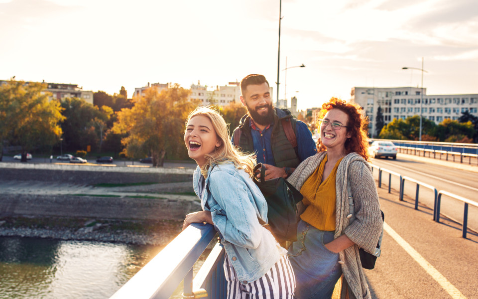 Junge Freunde haben Spa&szlig; beim Spaziergang durch die Stadt w&auml;hrend des Sonnenuntergangs.