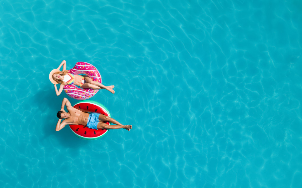 Ein Mann und eine Frau lassen sich auf einem Schwimmreifen im Pool treiben