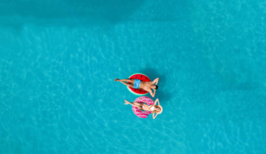 Eine Frau und ein Mann lassen sich auf einem Reifen im Pool treiben 